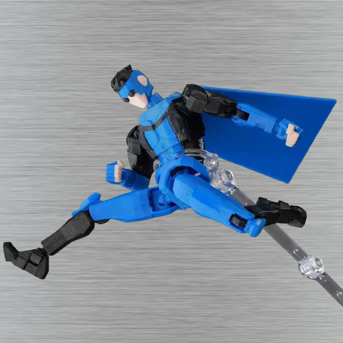 Toy figure in blue and black costume with cape on a textured gray background