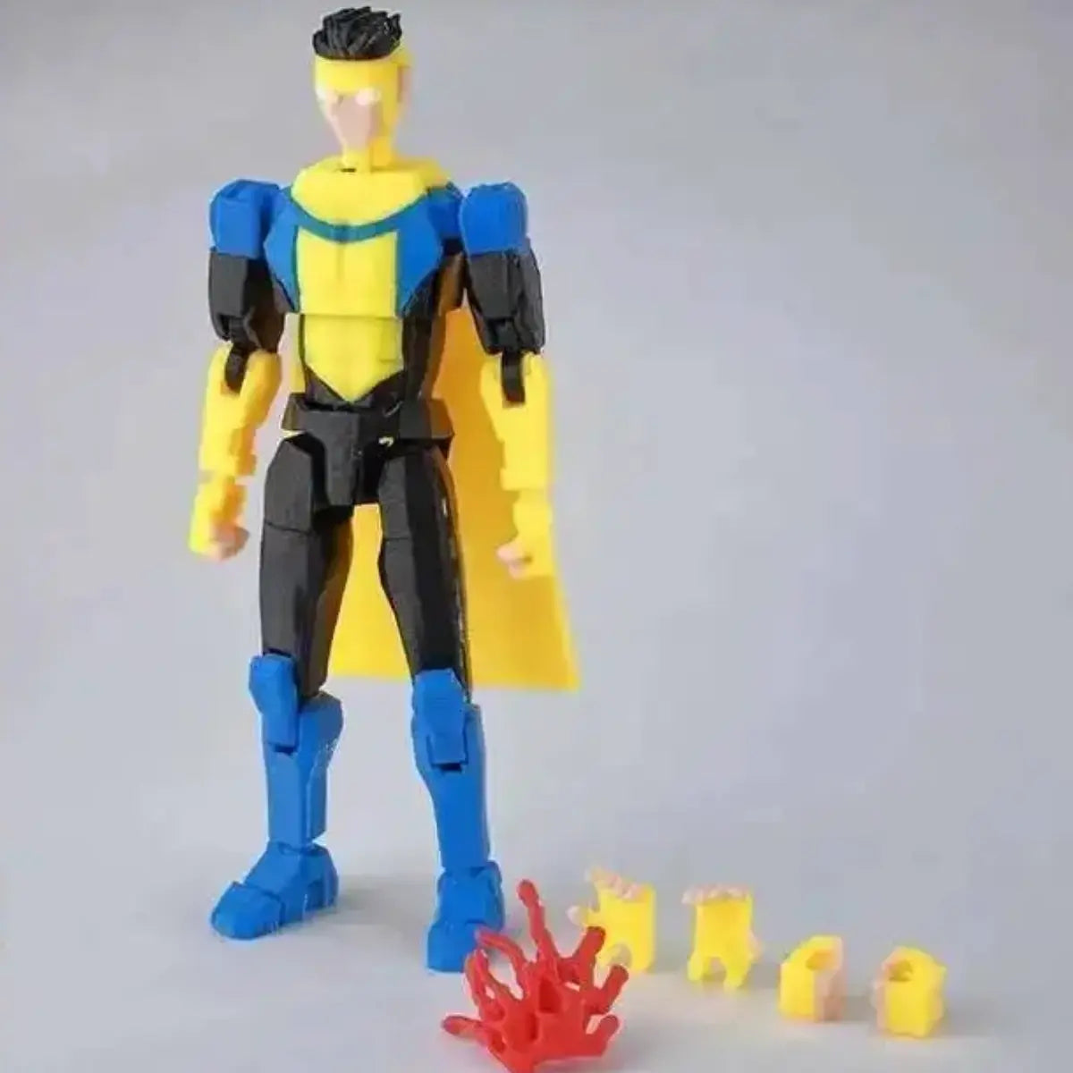 Superhero action figure with yellow cape and blue accents on a gray background