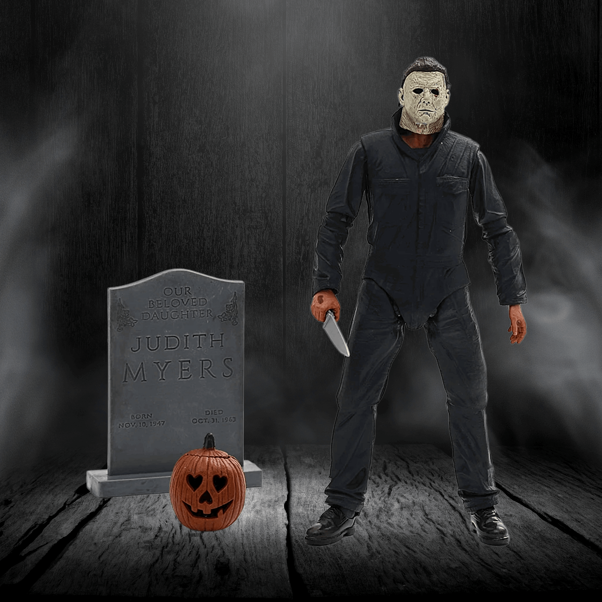 Action figure of a character holding a knife next to a tombstone and pumpkin in a dark setting