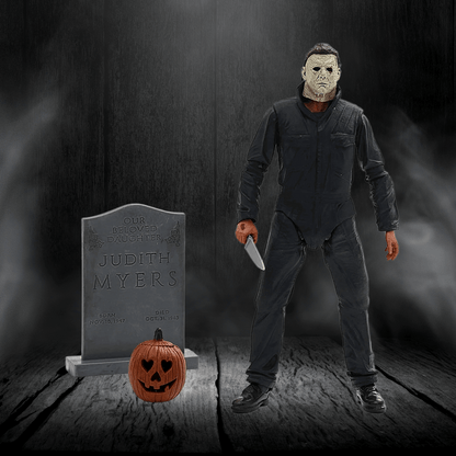 Action figure of a character holding a knife next to a tombstone and pumpkin in a dark setting