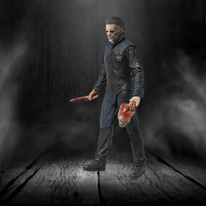Action figure holding a knife and a head in a dark, smoky setting
