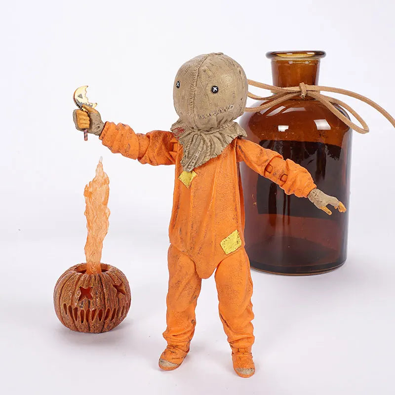 Vintage-style scarecrow figure with a candle and pumpkin next to an amber glass bottle on a white background