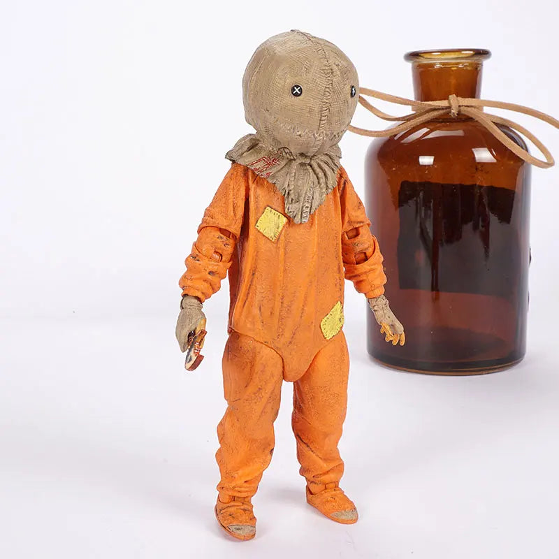 Scarecrow figure in an orange suit next to a brown bottle on a white background