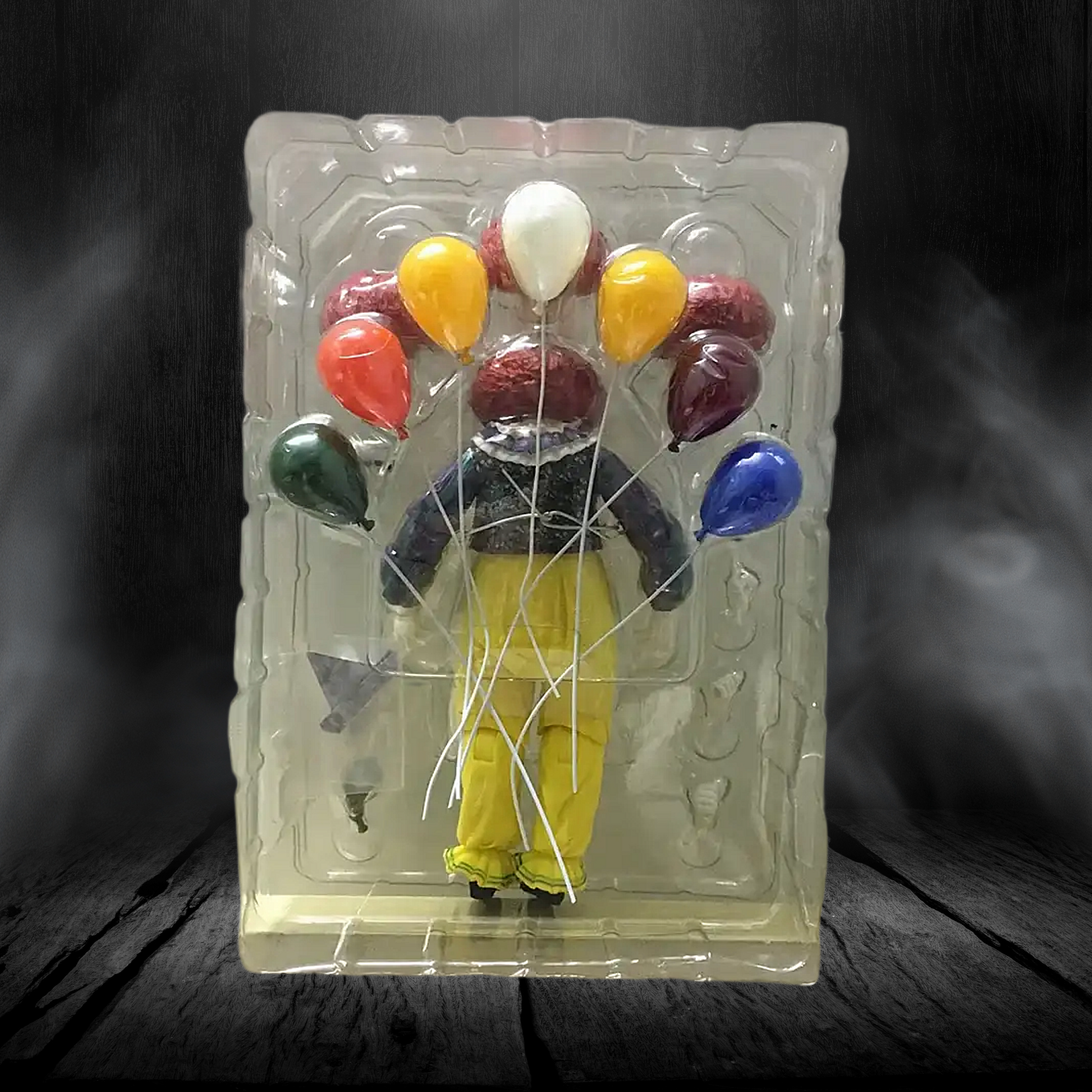 Figurine of a person with balloons in clear packaging on a dark background