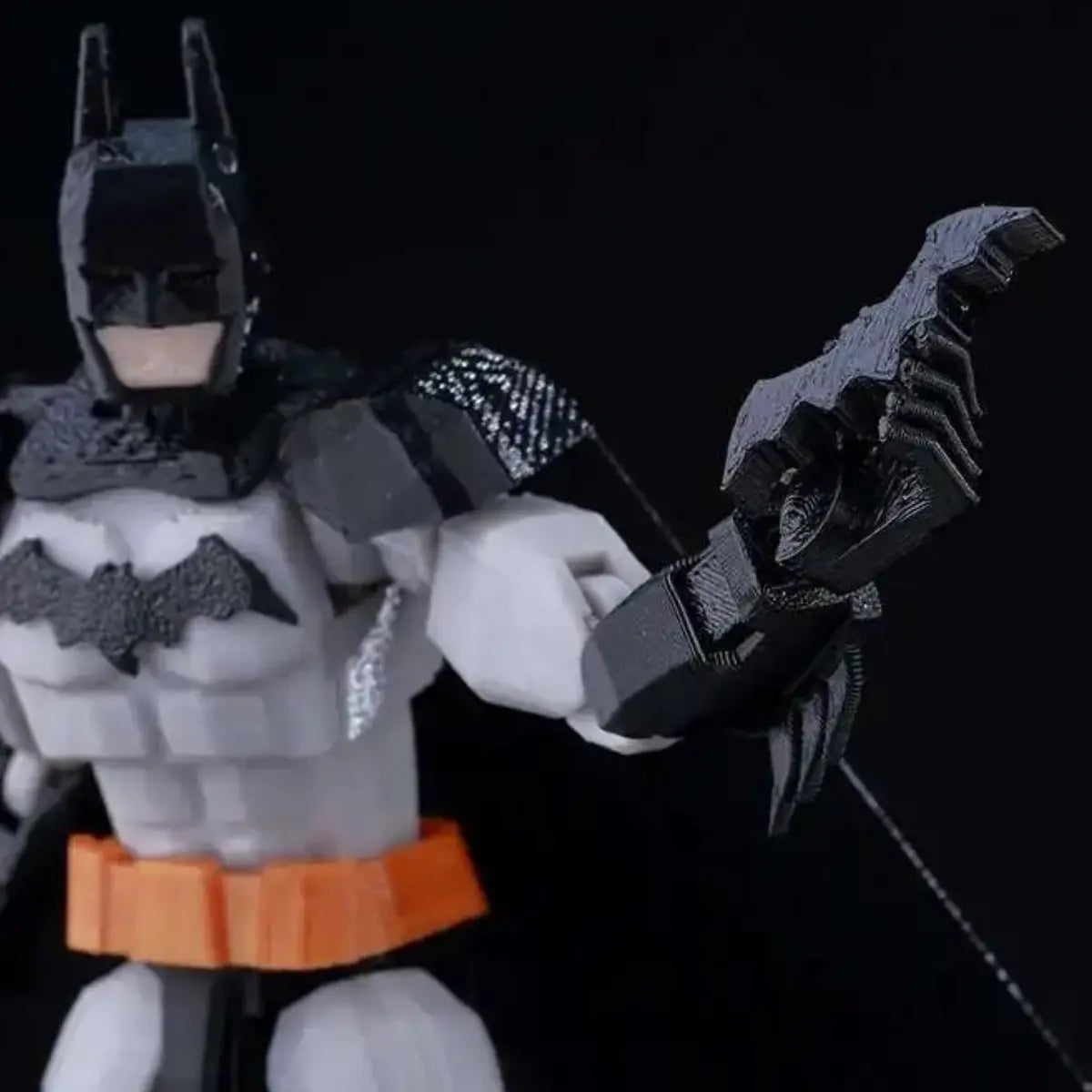 Batman action figure with a large weapon on a black background