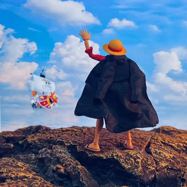 Person in a large coat and yellow hat standing on a rocky outcrop with a colorful kite in the sky.