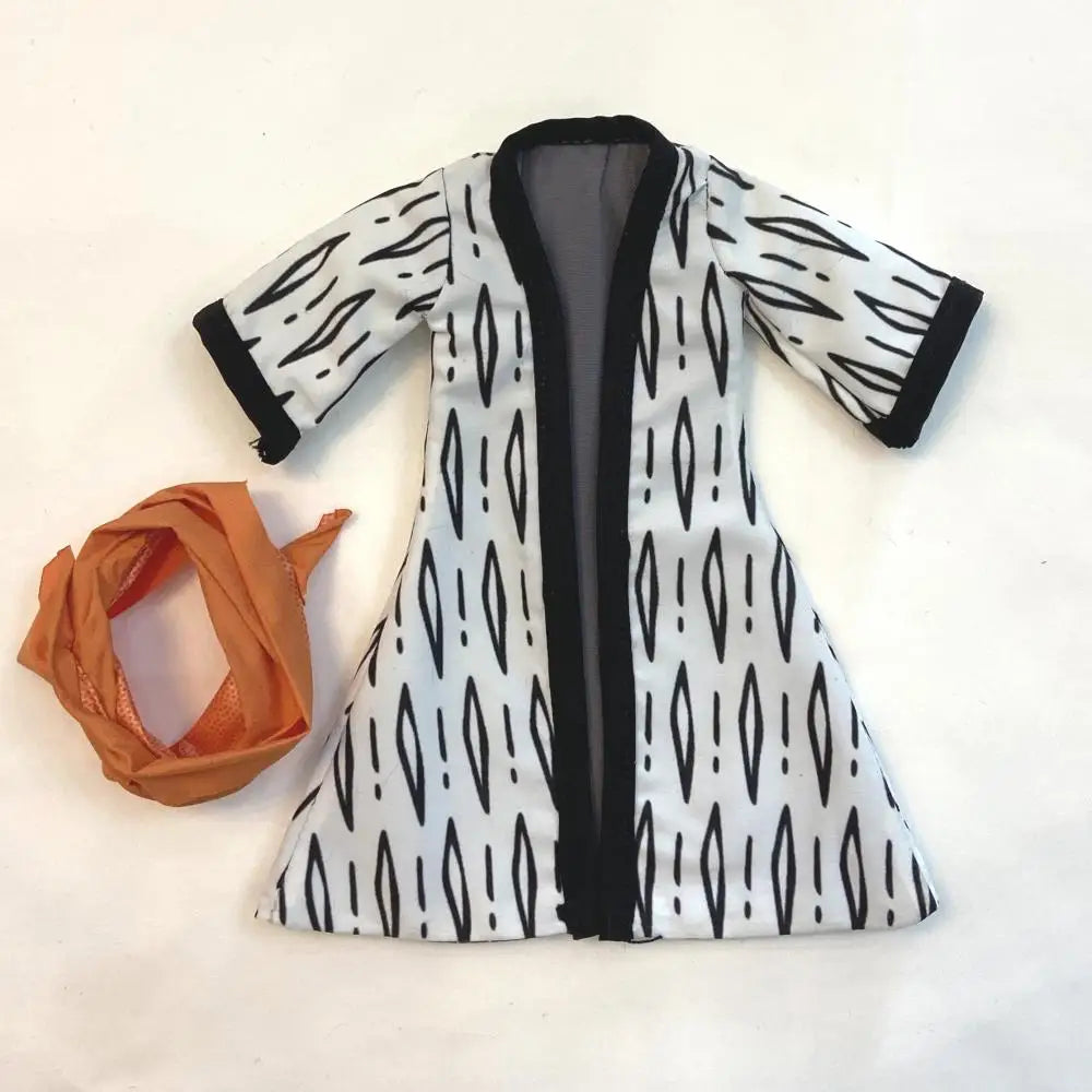 White cardigan with black pattern and orange scarf on a white background