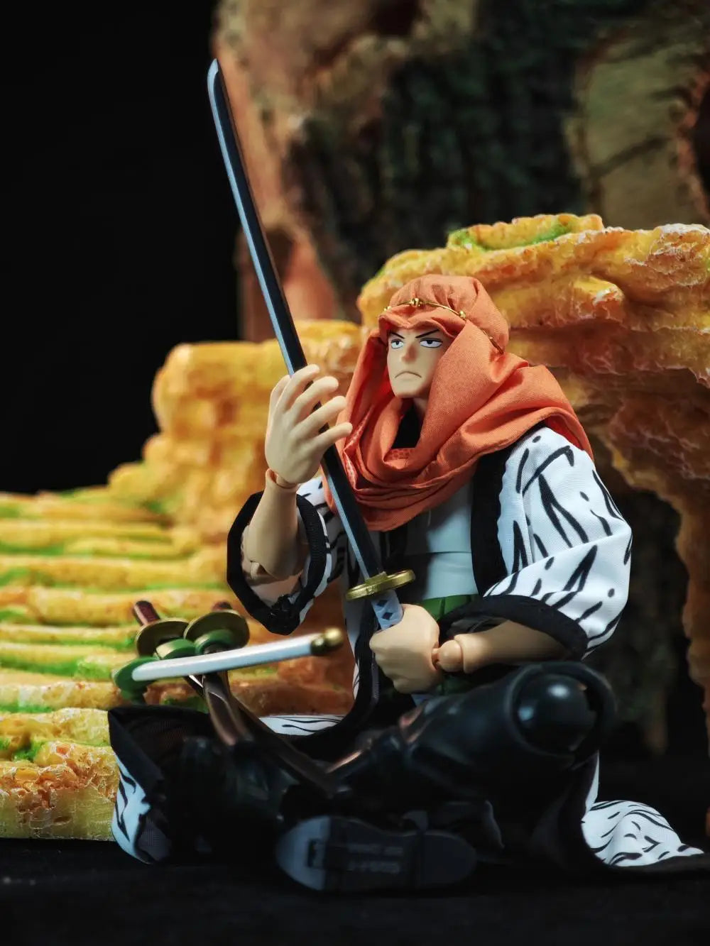 Figurine of a character with a sword, wearing an orange headscarf, against a background of stacked food items.