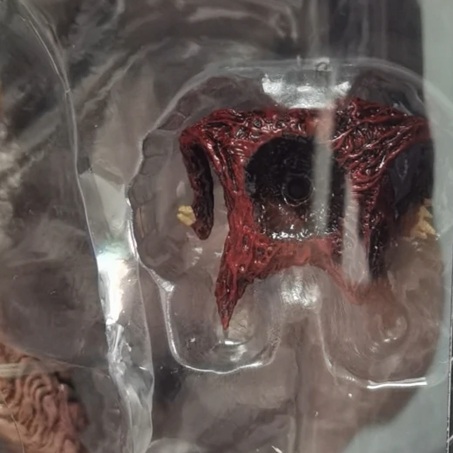 Red and black decorative item in clear packaging on a textured surface